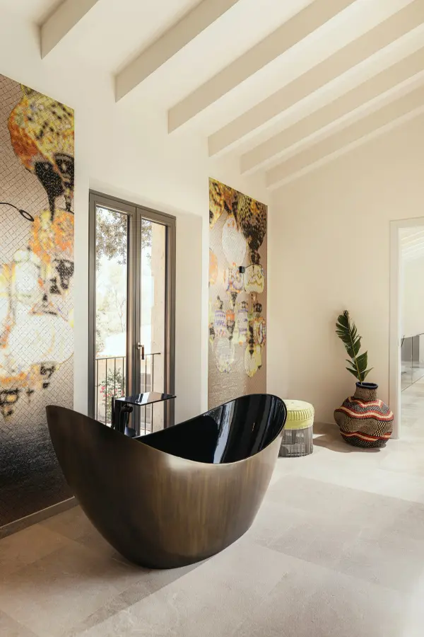 Badezimmer mit freistehender Bronzewanne und Mosaikkunst an der Wand auf Mallorca