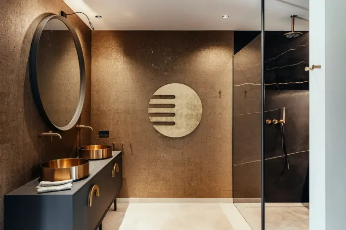 Badezimmer in warmen Brauntönen mit Rundspiegel, Kupferbecken und begehbarer Dusche
