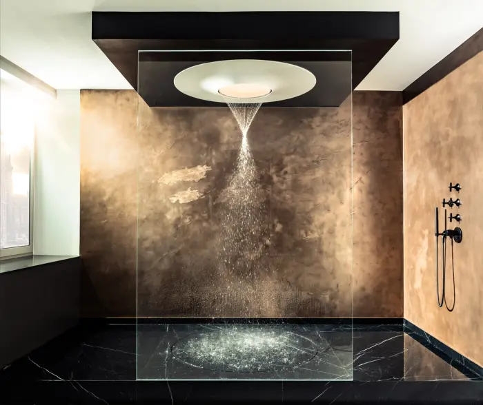 Showroom bei PORT1: Regendusche mit Deckenbrause vor goldener Wand und schwarzem Marmorboden