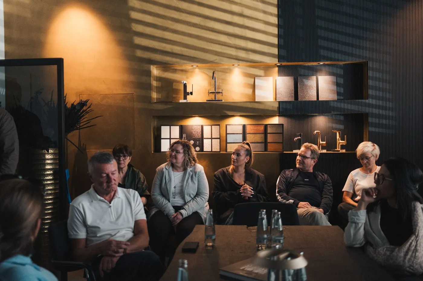 Teilnehmende eines Seminars zur Referenzfotografie an langen Tischen in einem Bad-Showroom